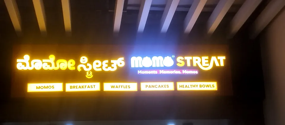 Momo Streat board at night: bilingual lit letters with menu strip