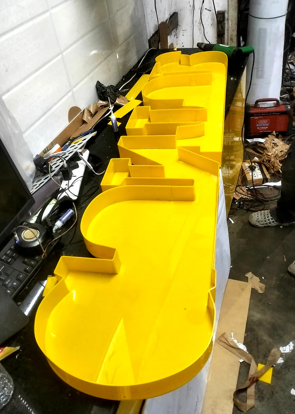 Bright yellow channel letters lined up on the workbench after bending